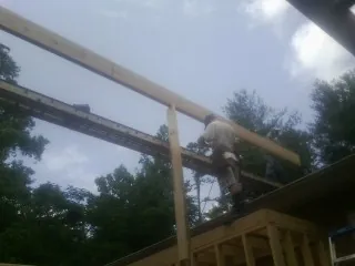 Carpenter setting a ridge beam over a new addition frame — Ice Dam Removal by Roofing Brothers in Stow