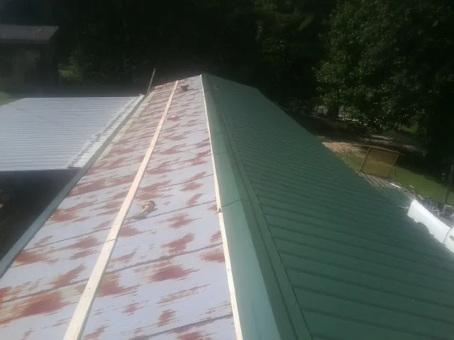 Old rusted panels beside newly installed green metal roofing — Wind Damage Roof Repair by Roofing Brothers in Stow