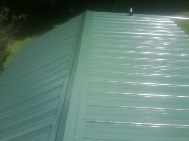 New green metal panels meeting at the ridge of a roof — Flat Roof Repair work by our crew in Stow