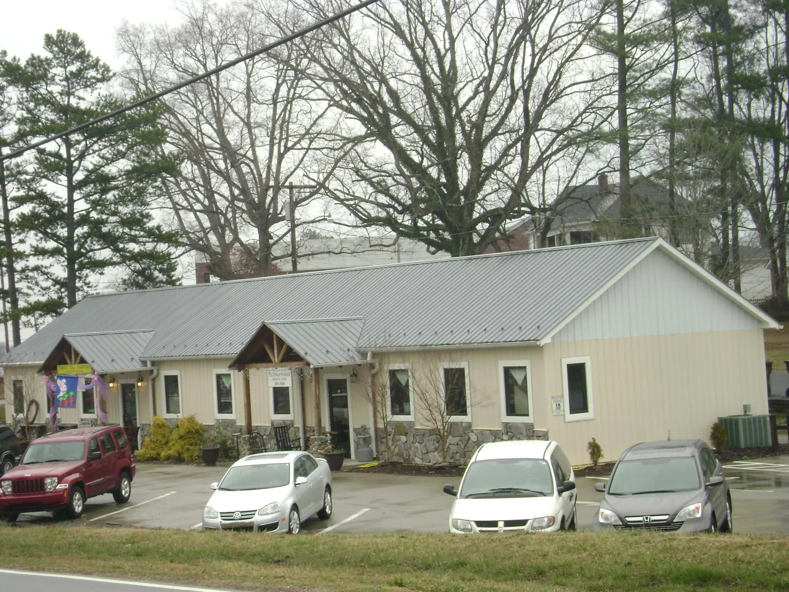 Gray metal roof with timber entry brackets on a small commercial building in Stow
