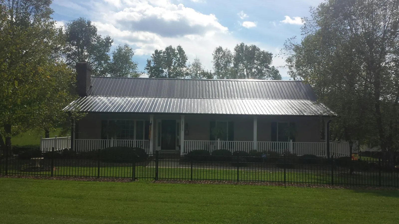 Gray metal roof on a brick ranch with a full width front porch — Gutter Guard Installation work by our crew in Stow