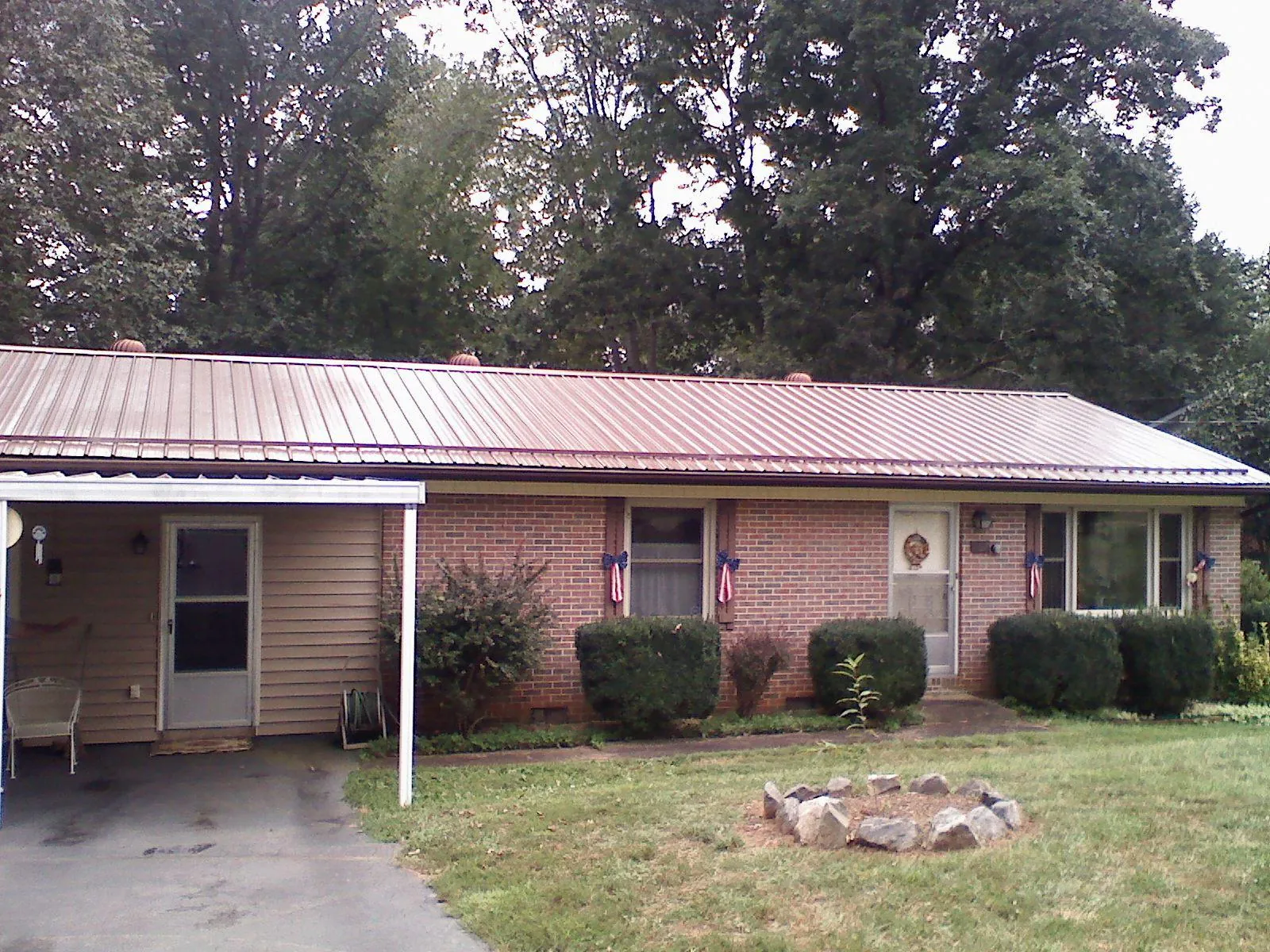 Bronze metal roof and carport on a brick ranch home — Roof Repair work by our crew in Stow